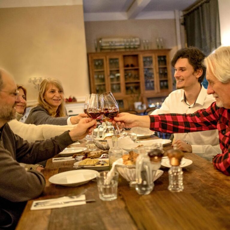 Guests raising a toast with red wine at a long table on a Bratislava food tour