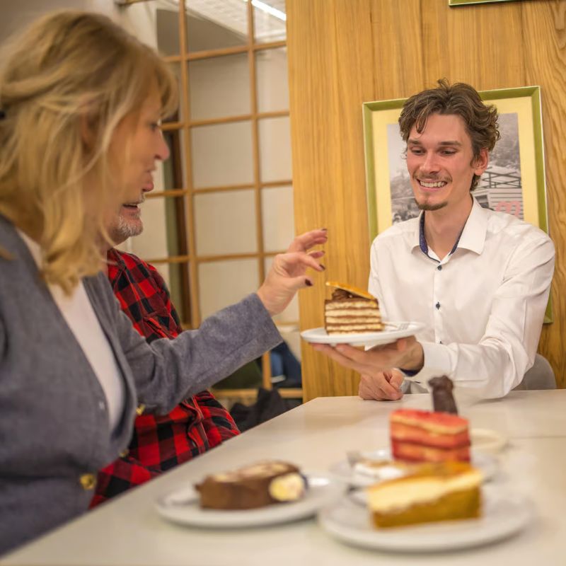 Friends sharing traditional Bratislava cakes inside a cozy local cafe.