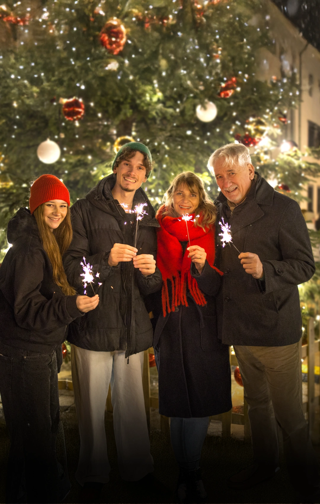Happy tourists holding sparklers during a festive Bratislava Christmas Markets Food Tour at night.