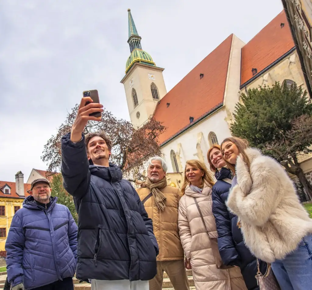 Smiling tourists during a walking tour at St. Martin's Cathedral, a major landmark in Bratislava's Old Town.