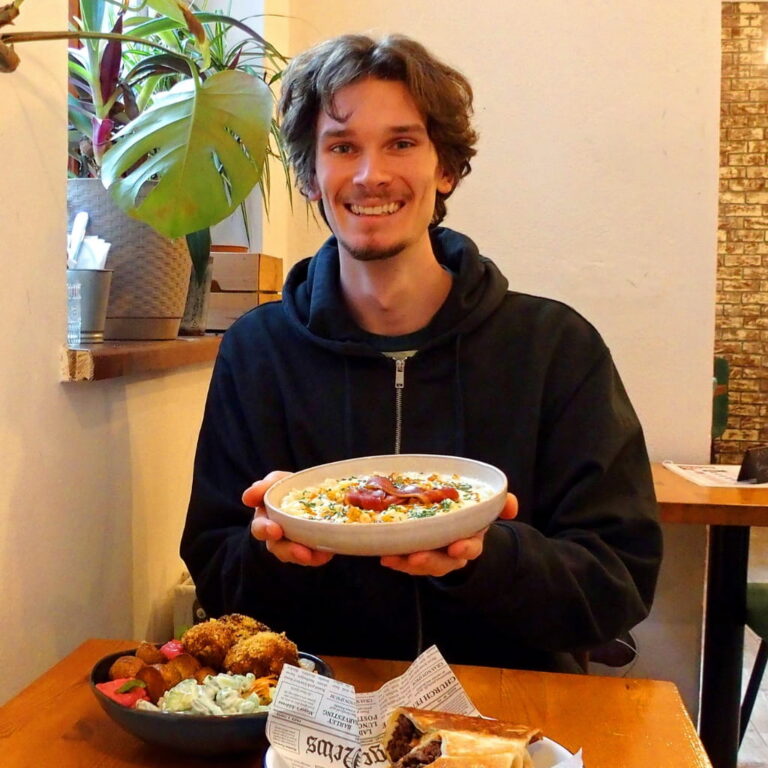 Guide Jakub holding a plate of traditional food in a Bratislava restaurant