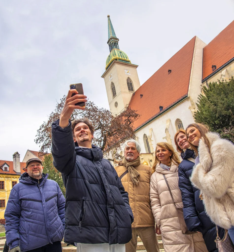 Tour group taking a selfie with guide Jakub in front of a church in Bratislava